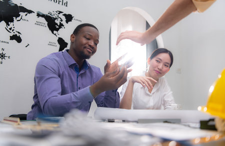 Multiethnic team of architects and designers are meeting new project, He carries a light bulb that should not be used in buildings because it is not energy efficient and not earth-friendly.の写真素材
