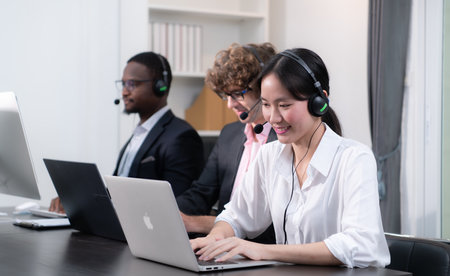 Group of business people wearing headset working actively in office. Call center, telemarketing, customer support agent provide service on telephone video conference call.の写真素材
