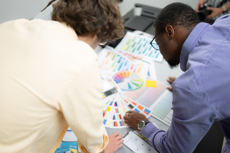 Multiethnic team of architects and designers are meeting to brainstorm design an application smartphone on a bright modern office working on a laptop.の写真素材