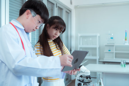 In the science classroom, an Asian child scientist experimenting with scientific formulas with chemicalsの写真素材
