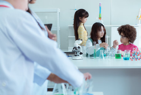 In the science classroom, an Asian child scientist experimenting with scientific formulas with...