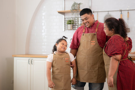 A plus-size family with a father wearing a prosthetic leg, Eat together after cooking and daughter drinks milk for health in the dining room of the houseの写真素材
