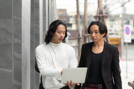 Group of business people walking and working on laptop computer in side of modern office building. Multiethnic group of business people using digital devices outdoor.の写真素材