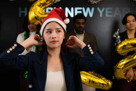 Asian woman in a Santa hat with gold balloons on the background at New Year's Eve partyの写真素材