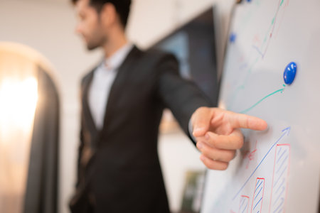 Businessman pointing on flip chart in office, focus on hand.の写真素材