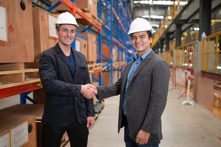 Two businessmen shaking hands in a warehouse It is a warehouse of spare parts and equipment for...