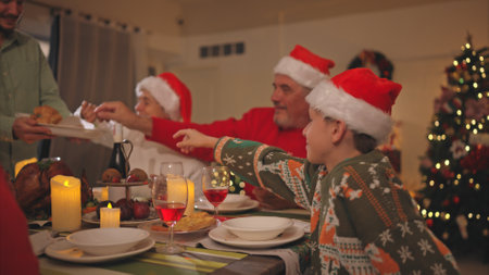 A close-up of a senior couple as their son delivers a snack of bread before the main meal at christmas nightの写真素材
