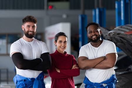 Portrait of two guy professional auto technician and a female customer standing in an auto repair...