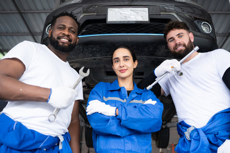 Portrait of smiling team of mechanics looking at camera while standing under carの写真素材