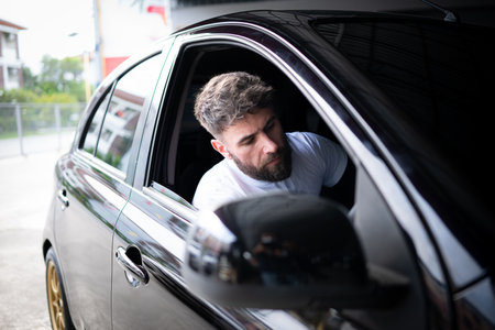 A young man vehicle technician working inside a car at an auto repair shop.の写真素材