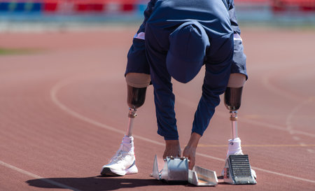 Disabled athletes prepare in starting position ready to run on stadium trackの写真素材
