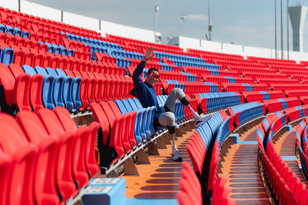 Disabled athletes prepare their bodies on amphitheater in a sports arena on a sunny day before entering a short-distance running competitionの写真素材