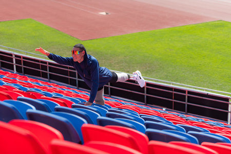 Disabled athletes prepare their bodies on amphitheater in a sports arena on a sunny day before entering a short-distance running competitionの写真素材