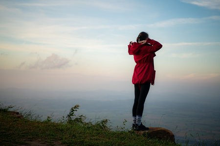 Portrait of a beautiful young woman in red coat on the background of blue sky