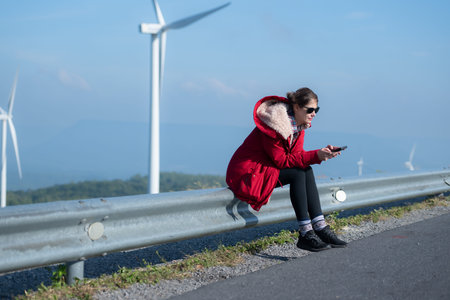 On the background of windmills, A young woman in a red jacket is enjoying her winter vacation.