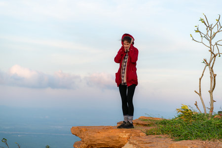 Portrait of a beautiful young woman in red coat on the background of blue skyの写真素材
