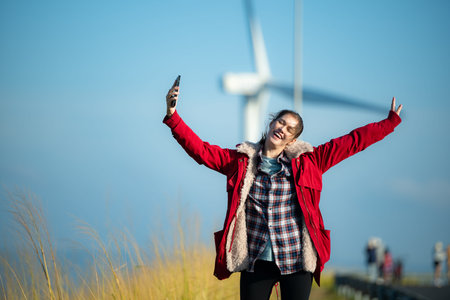 On the background of windmills, A young woman in a red jacket is enjoying her winter vacation.