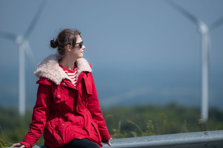 On the background of windmills, A young woman in a red jacket is enjoying her winter vacation.