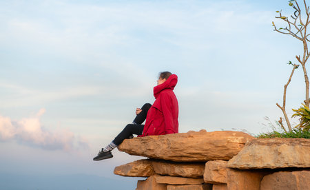 Portrait of a beautiful young woman in red coat on the background of blue skyの写真素材