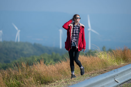 On the background of windmills, A young woman in a red jacket is enjoying her winter vacation.
