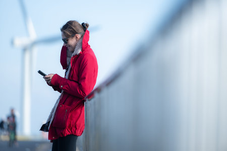 On the background of windmills, A young woman in a red jacket is enjoying her winter vacation.