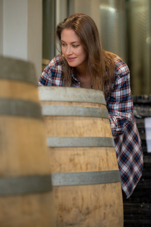 Portrait of a young woman surrounded by wine barrels In her wineryの写真素材
