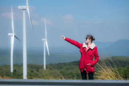 On the background of windmills, A young woman in a red jacket is enjoying her winter vacation.の写真素材