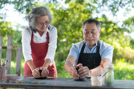 In the pottery workshop, an Asian retired couple is engaged in pottery making and clay painting activities.の写真素材