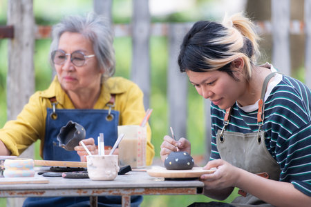 In the pottery workshop, an Asian retired couple is engaged in pottery making and clay painting activities.の写真素材