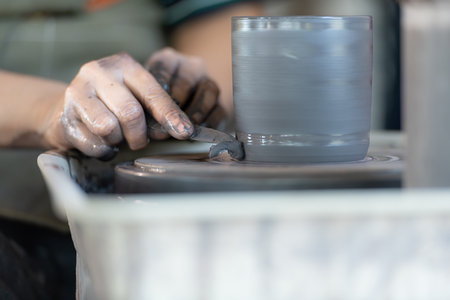 hands of a potter, creating an earthen jar on the pottery wheelの写真素材
