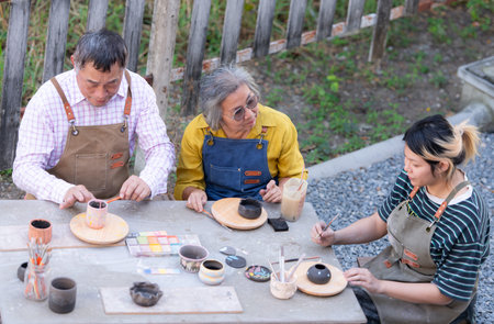 In the pottery workshop, an Asian retired couple is engaged in pottery making and clay painting...