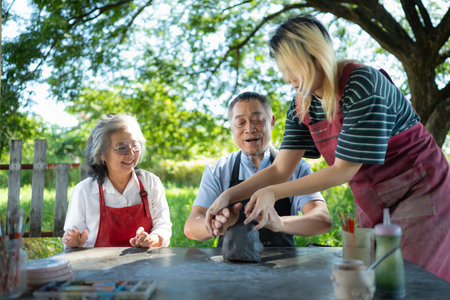 In the pottery workshop, an Asian retired couple is engaged in pottery making and clay painting activities.の写真素材