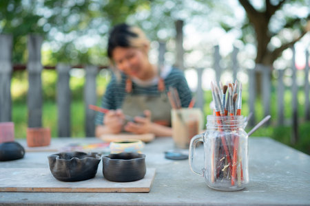 In the pottery workshop, Asian woman is engaged in pottery making and clay painting activities.の写真素材