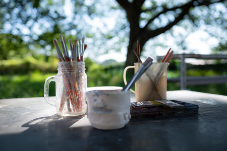 Paint brushes in glass jar on wooden table in the garden for preparing to paint pottery.の写真素材