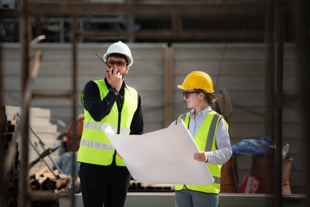 Engineer and architect working on the construction site, double-checking plans and process.の写真素材
