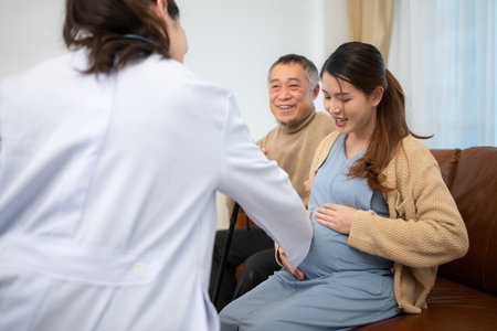 Father and daughter pregnant woman visit gynecologist doctor at medical clinic for pregnancy consultant. Doctor examine pregnant belly for baby and mother healthcare check up.の写真素材