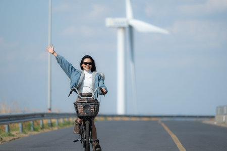 Young woman riding a bike on a road in a windmill.