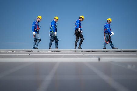 Group of engineers standing on solar panels with blue sky in the backgroundの写真素材