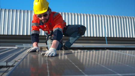 Technician working on the solar panel on the warehouse roof to inspect the solar panels that have...