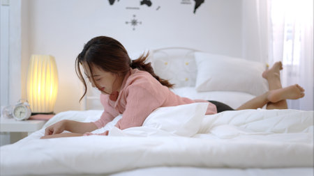 Asian young woman relaxing before bedtime on the bed in the bedroomの写真素材