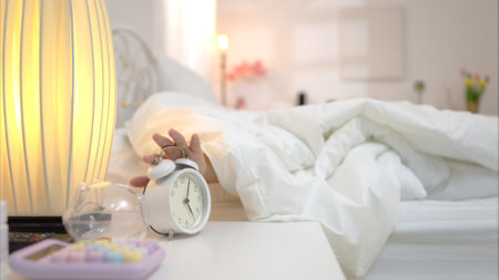Asian young woman on the bed in the bedroom trying to wake up and prepare for workの写真素材
