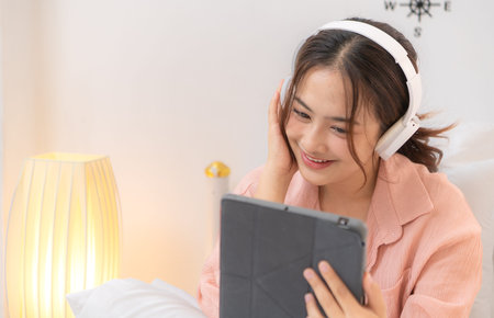 Asian young woman relaxing before bedtime on the bed in the bedroomの写真素材