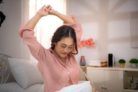 Asian young woman relaxing before bedtime on the bed in the bedroomの写真素材
