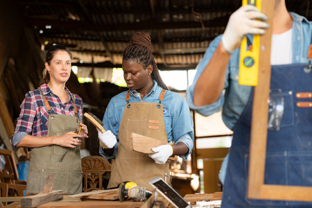 Portrait of carpenter male worker standing in front of colleague in workshop, Eyesight is utilized to ensure accuracy.の写真素材