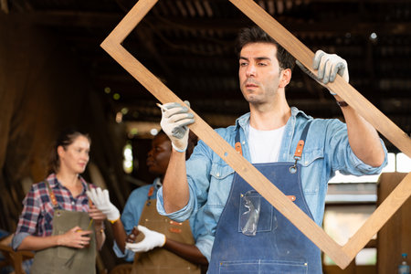 Portrait of carpenter male worker standing in front of colleague in workshop, Eyesight is utilized to ensure accuracy.の写真素材