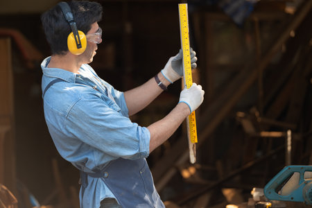 Portrait of a carpenter holding a spirit level in his workshop.の写真素材