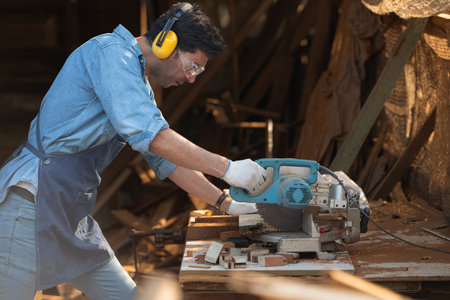 Portrait of a craftsman working with a circular saw at a wood workshopの写真素材