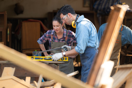Carpenter and his assistant working together in a carpentry workshopの写真素材