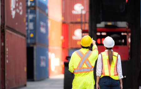Portrait of Asian woman engineer and worker working with co-worker at overseas shipping container...