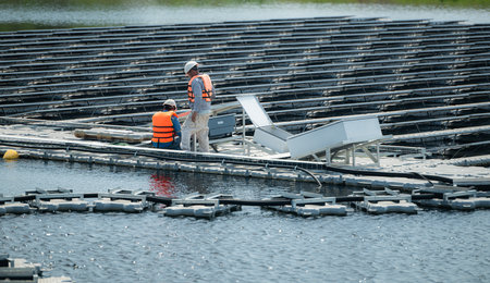 Both of technicians are currently evaluating and repairing the transmission terminals for electricity generated by solar energy in a floating solar power system.の写真素材